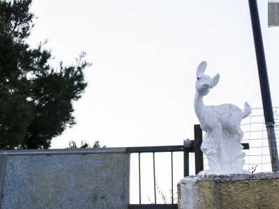 Un cerbiatto di gesso si erge sul cancello di una villa 
